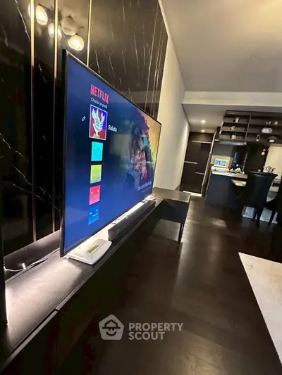 Modern living room with sleek TV setup and elegant dark wood flooring.