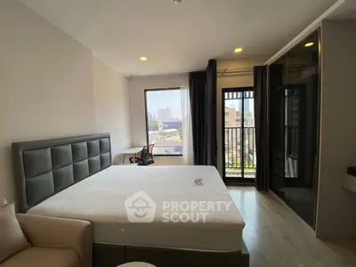 Spacious bedroom with city view and balcony access in modern apartment