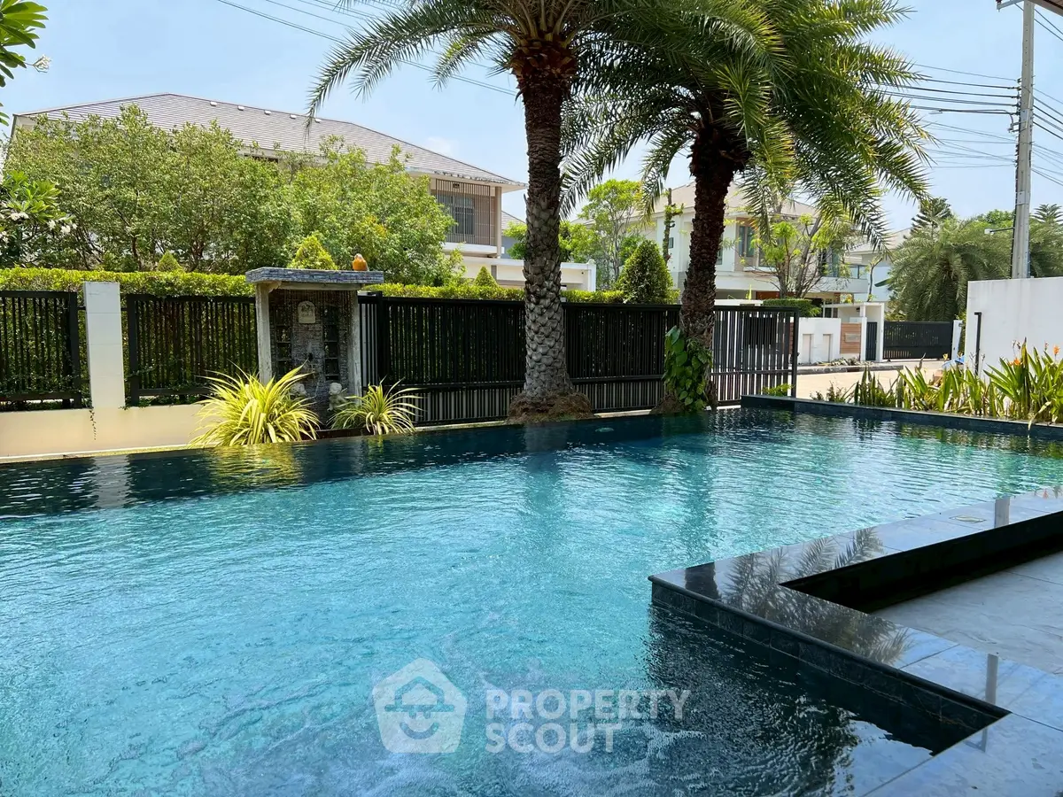 Luxurious outdoor pool with palm trees in a serene residential setting, perfect for relaxation and leisure.