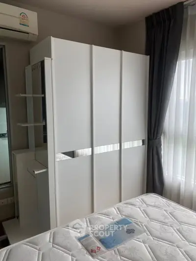 Modern bedroom with sleek white wardrobe and large window for natural light.