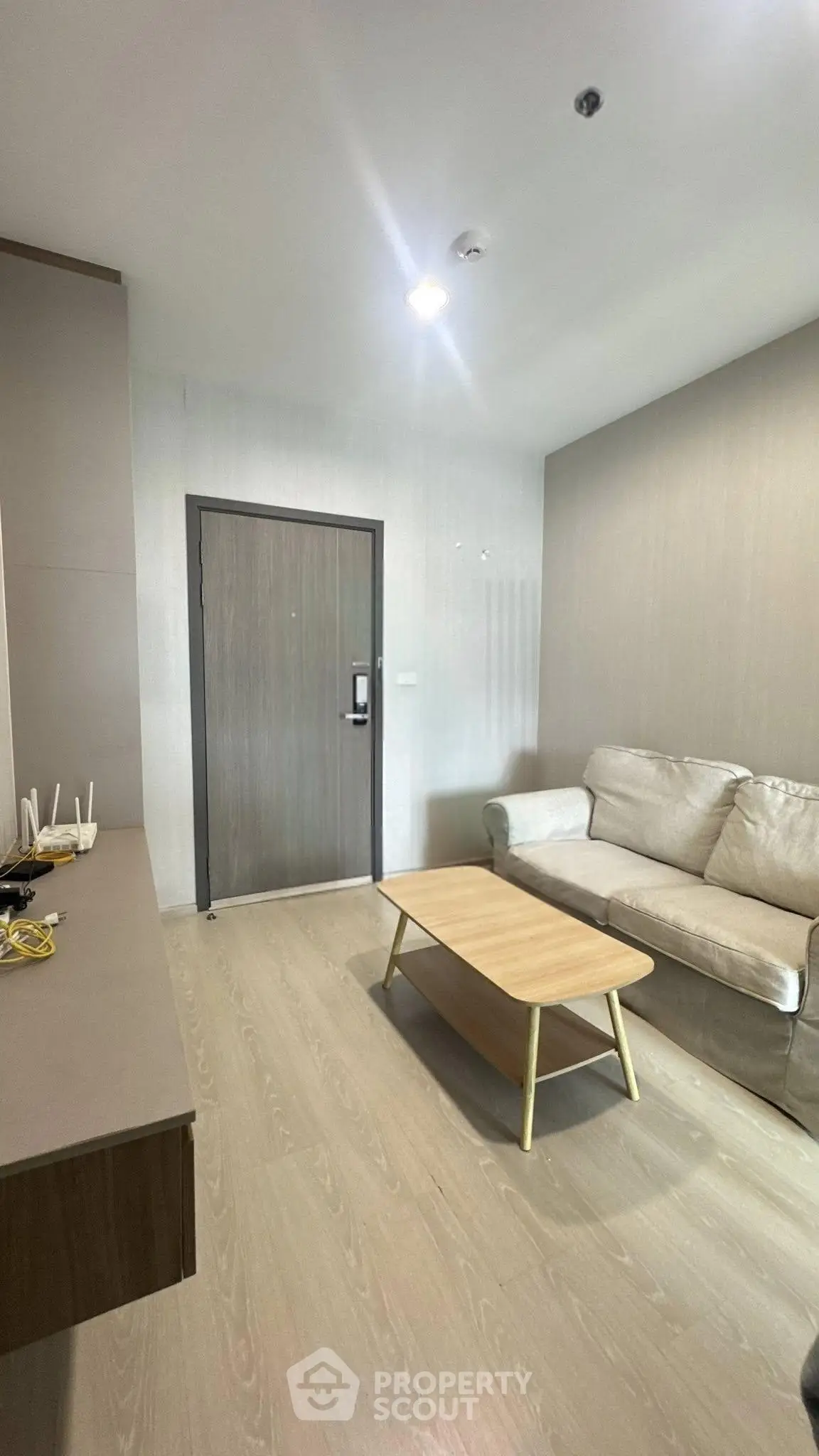 Modern living room with beige sofa and wooden coffee table in a cozy apartment.