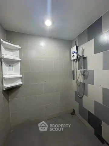 Modern bathroom with sleek gray tiles and wall-mounted shower unit.