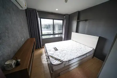 Modern bedroom with large window and stylish decor in urban apartment.