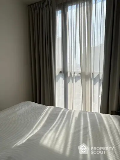 Cozy bedroom with soft natural light filtering through elegant curtains.