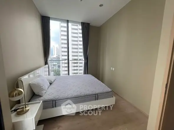 Modern bedroom with city view and stylish decor in high-rise apartment.