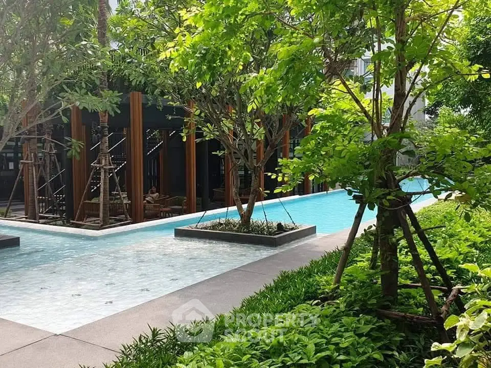 Luxurious outdoor pool surrounded by lush greenery in a modern residential complex.