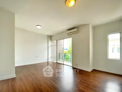 Spacious empty living room with wooden flooring and balcony access