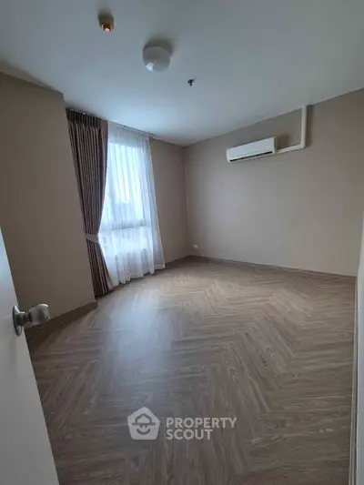 Spacious empty bedroom with wooden flooring and natural light