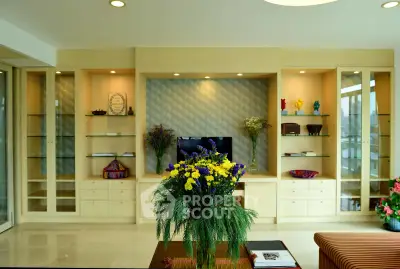 Elegant living room with built-in shelves and modern decor, featuring a vibrant floral centerpiece.