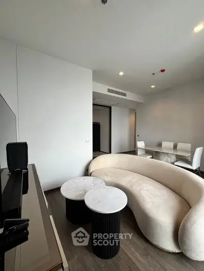 Modern living room with stylish curved sofa and elegant dining area in a contemporary apartment.