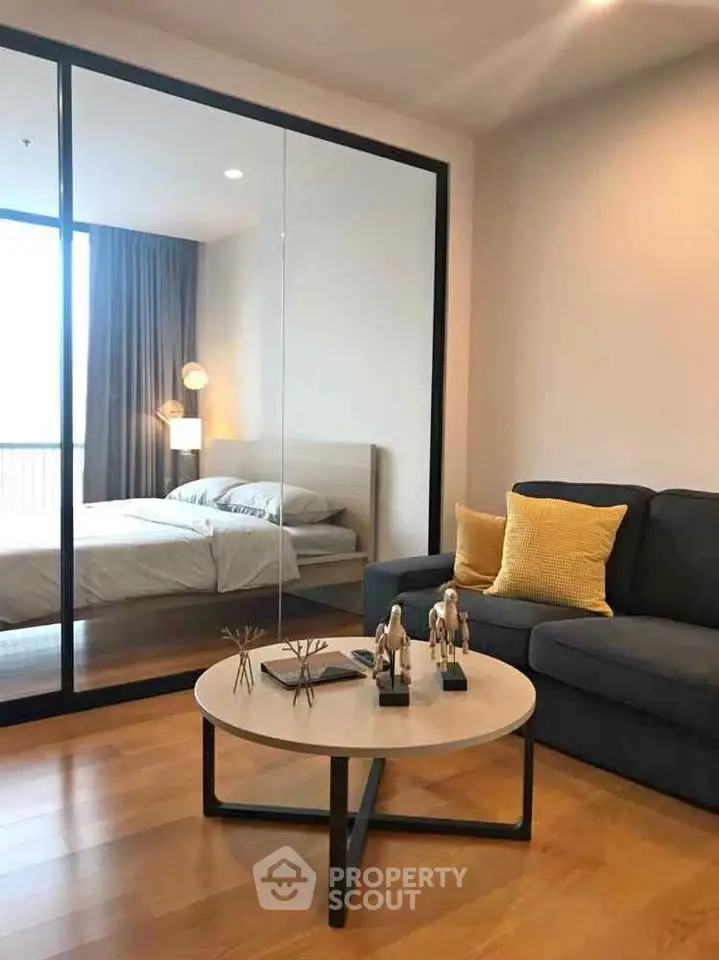 Modern apartment with cozy living room and stylish bedroom separated by glass wall.