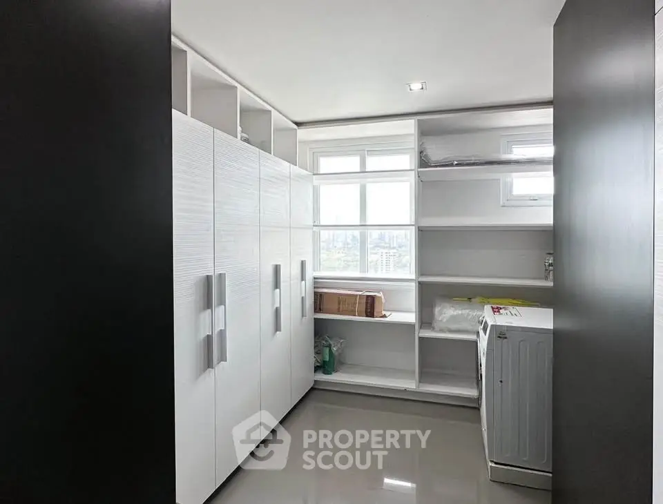 Spacious laundry room with ample storage and natural light in modern apartment.