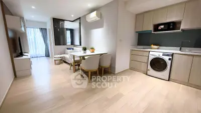 Modern open-plan living room with kitchen featuring washing machine and dining area.