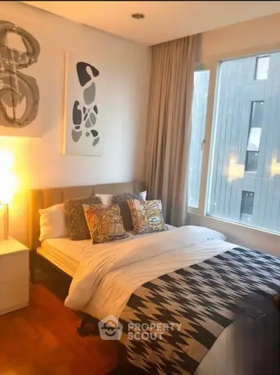 Cozy bedroom with modern decor and large window offering natural light.