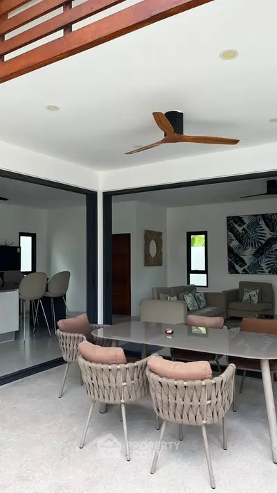Modern open-plan living area with stylish furniture and ceiling fan, perfect for indoor-outdoor living.