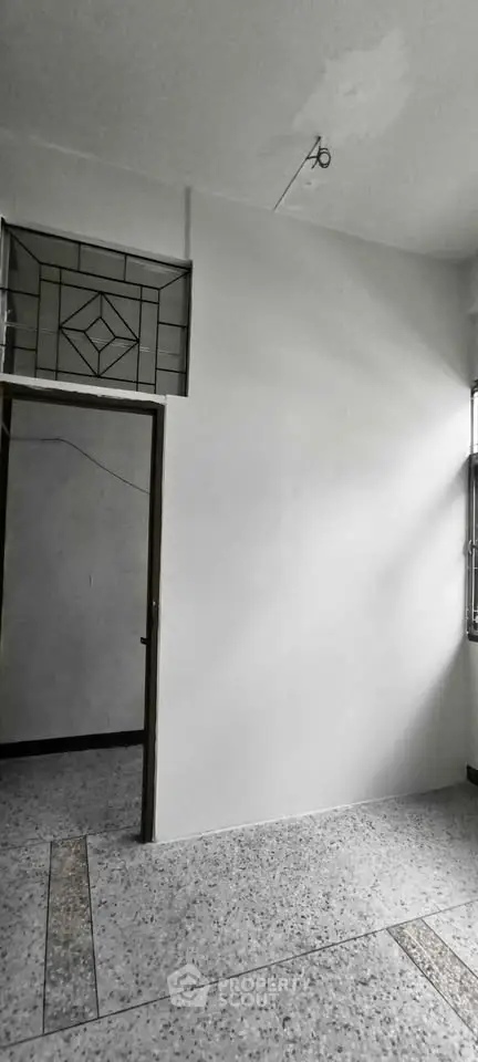 Spacious room with unique window design and terrazzo flooring