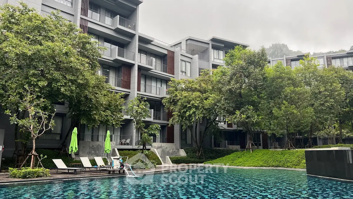 Luxurious modern apartment complex with pool and lush greenery, perfect for serene living.