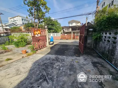 Spacious residential driveway with open gate and lush greenery