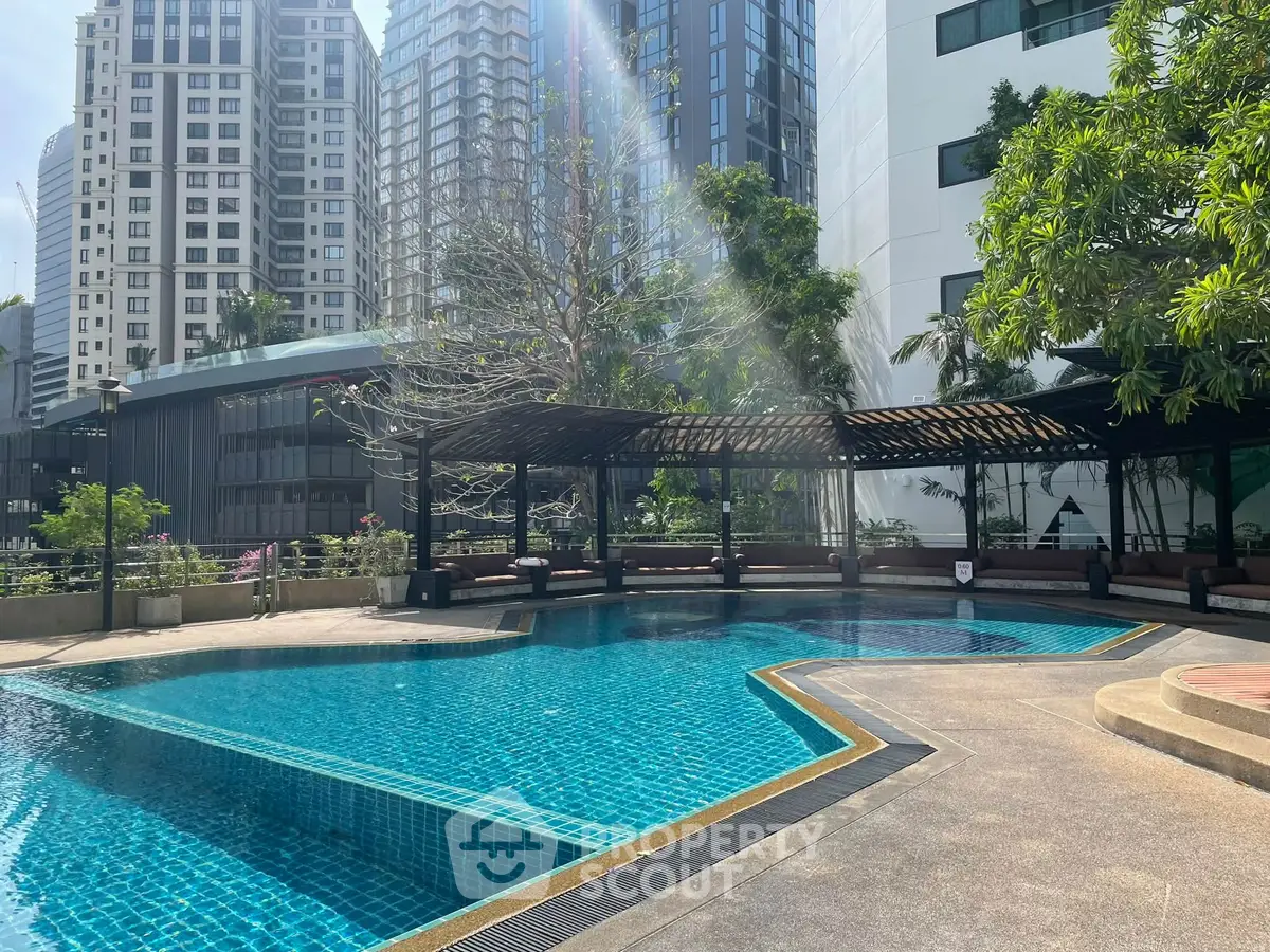 Luxurious outdoor pool area with modern cityscape backdrop, perfect for relaxation and leisure.