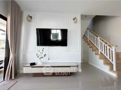 Modern living room with wall-mounted TV and stylish staircase in a bright, open space.