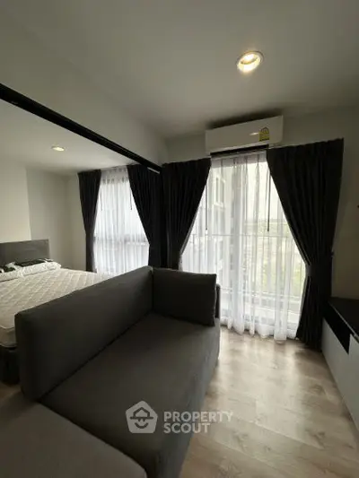 Modern bedroom with cozy sofa and large windows for natural light