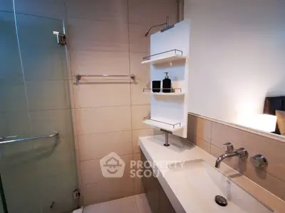 Modern bathroom with sleek fixtures and glass shower enclosure in contemporary apartment.