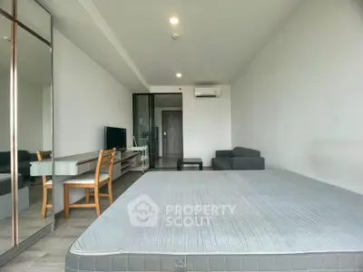 Spacious modern studio apartment with sleek furniture and ample natural light.