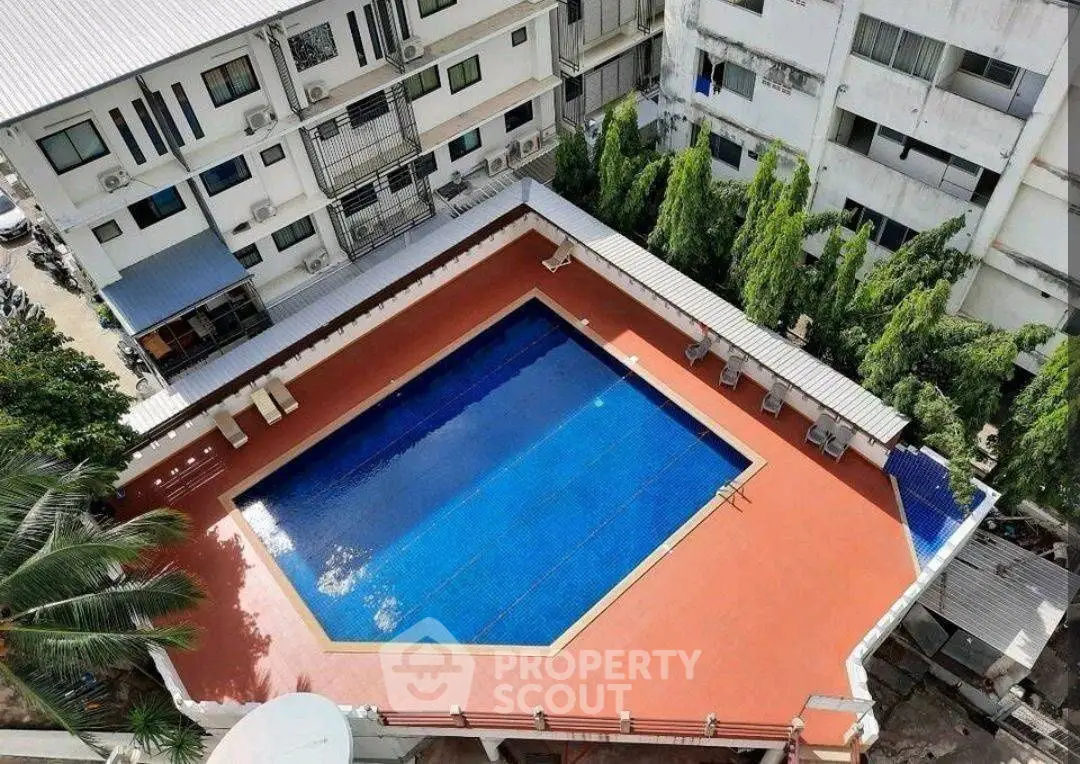 Stunning aerial view of a residential swimming pool surrounded by lush greenery and modern apartments.