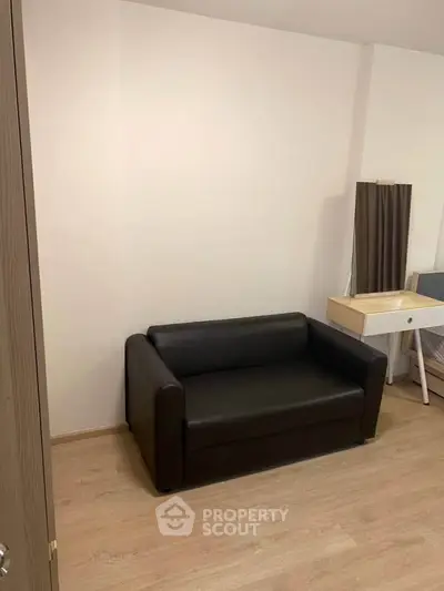 Cozy living room with modern black sofa and wooden flooring, perfect for relaxation.