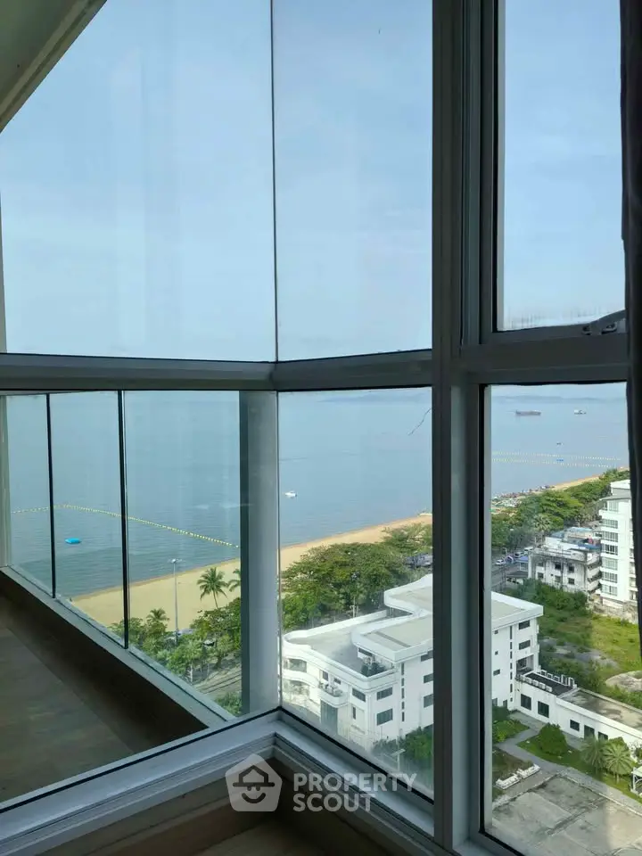 Stunning beachfront view from a high-rise apartment window, showcasing serene ocean and sandy shores.