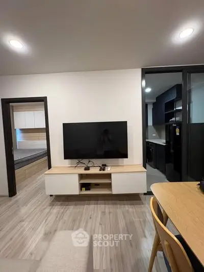 Modern living room with sleek TV setup and open view into stylish kitchen