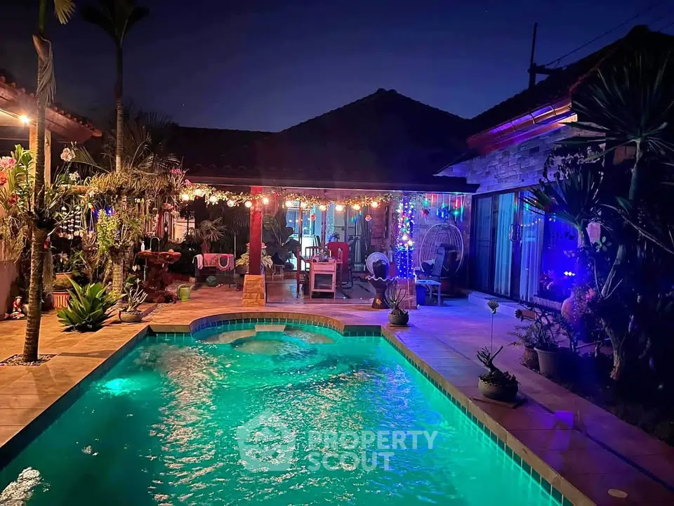 Stunning evening view of a luxurious backyard pool with ambient lighting and lush landscaping.