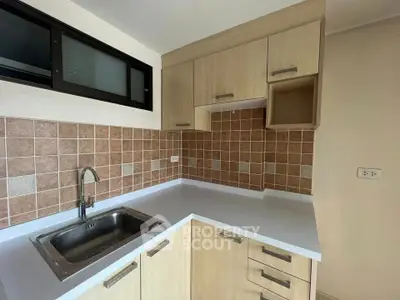 Modern kitchen with sleek cabinetry and tiled backsplash, featuring a stainless steel sink and ample counter space.