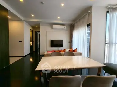 Modern living room with sleek design and natural light, featuring a marble dining table and cozy seating area.