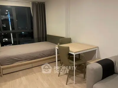 Modern studio apartment with bed, dining table, and city view window.