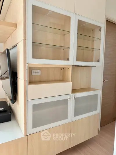 Modern built-in storage unit with glass cabinets and wood finish in a stylish living room.