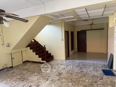 Spacious open-plan living area with tiled flooring and wooden staircase, ideal for customization.
