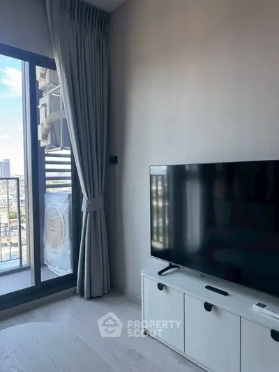 Modern living room with large TV and balcony view in high-rise apartment