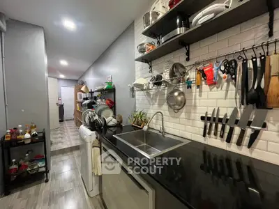 Modern kitchen with sleek black countertop and open shelving, featuring a stylish backsplash and stainless steel sink.