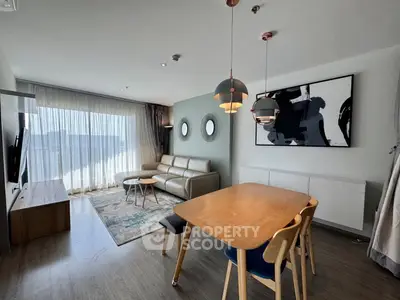 Modern living room with stylish decor and ample natural light, featuring a cozy seating area and dining space.