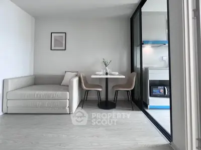 Modern living room with cozy sofa and dining area adjacent to sleek kitchen.