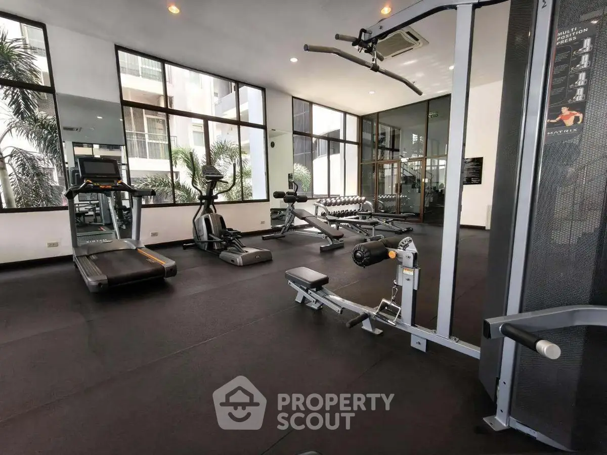 Modern gym with state-of-the-art equipment and large windows in a luxury residential building.