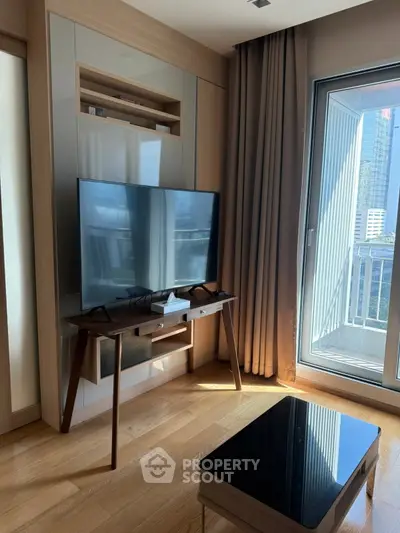 Modern living room with sleek TV, wooden flooring, and large window offering city view.