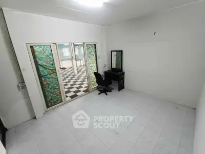 Spacious room with sliding glass doors and checkered floor tiles, ideal for versatile use.