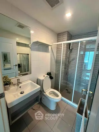 Modern bathroom with glass shower, sleek sink, and stylish tiles in a contemporary apartment.