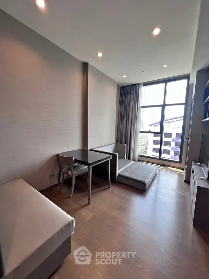 Modern living room with large window and stylish furniture in a high-rise apartment.