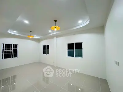 Spacious modern living room with elegant lighting and tiled flooring, perfect for family gatherings.