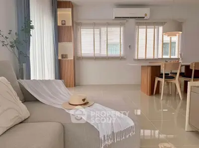 Modern living room with cozy sofa and dining area, featuring elegant decor and natural light.