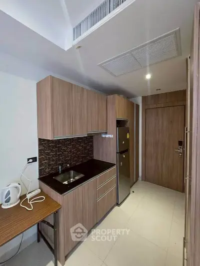 Modern compact kitchen with wooden cabinets and sleek appliances in a stylish apartment.