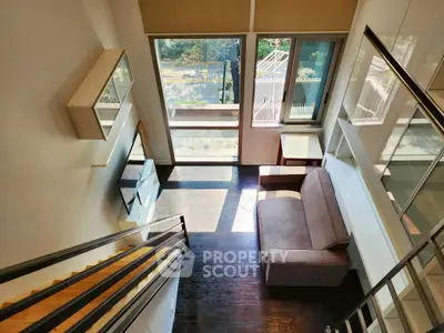 Modern loft-style living room with large windows and stylish staircase